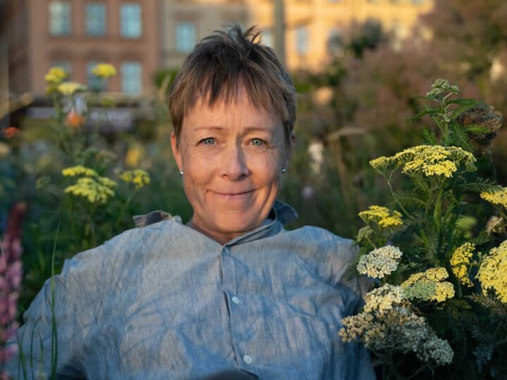 Sofia Eskilsdotter sitter bland växter utomhus.